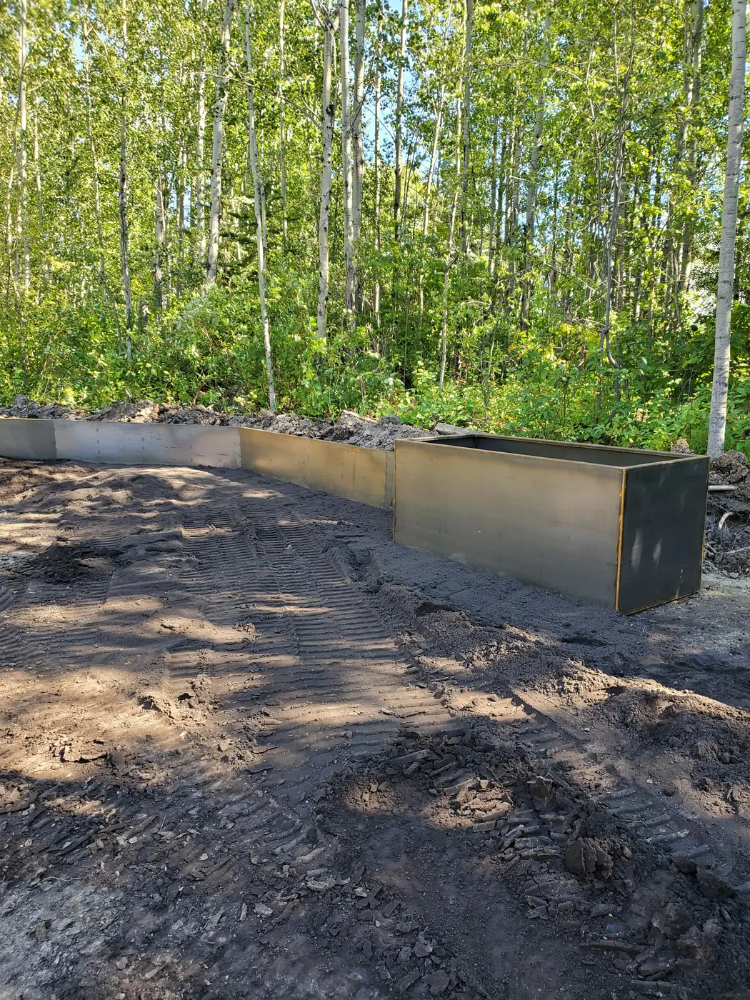 Tall rectangular Corten steel planter box newly installed in a wooded yard