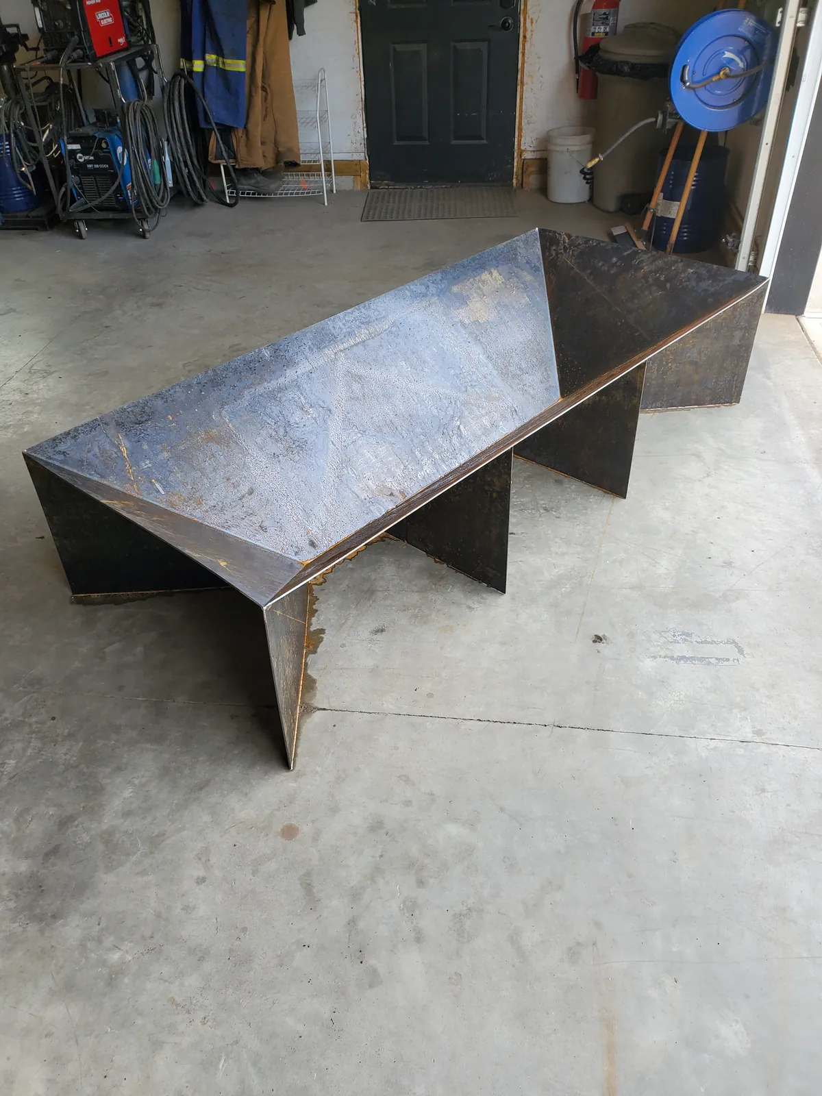 Angled view of a faceted steel fire pit in the fabrication shop