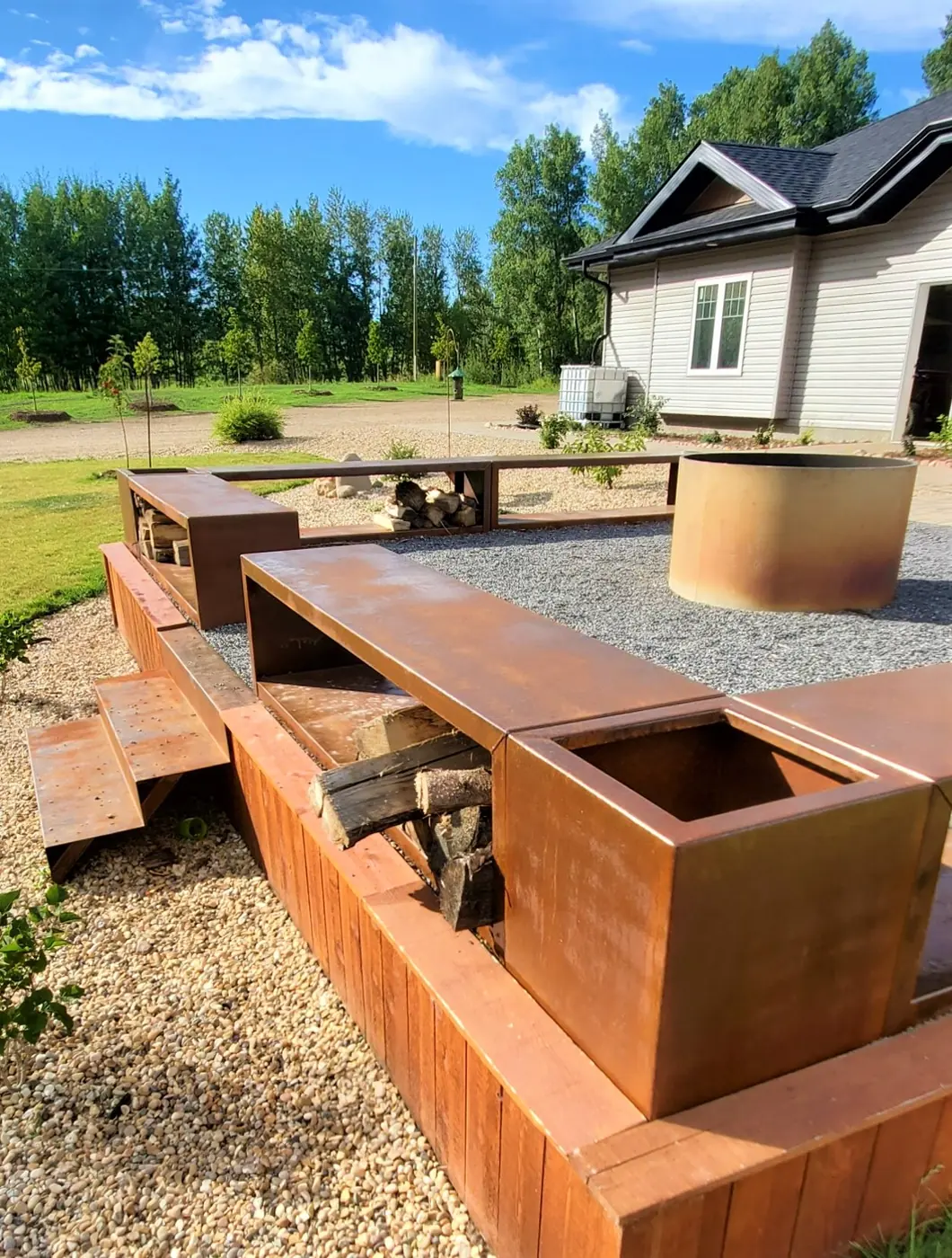 Close view of a Corten steel firewood bench with split-wood storage and a planter box