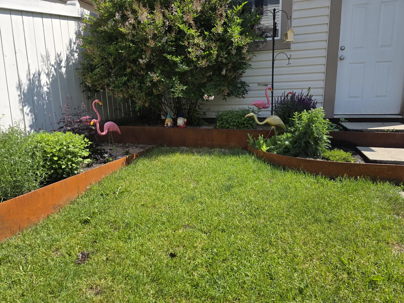 Corten steel edging defining a curved lawn in a landscaped front yard