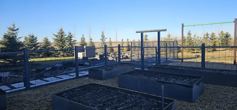 Custom steel garden fencing enclosing raised steel planter beds on an acreage