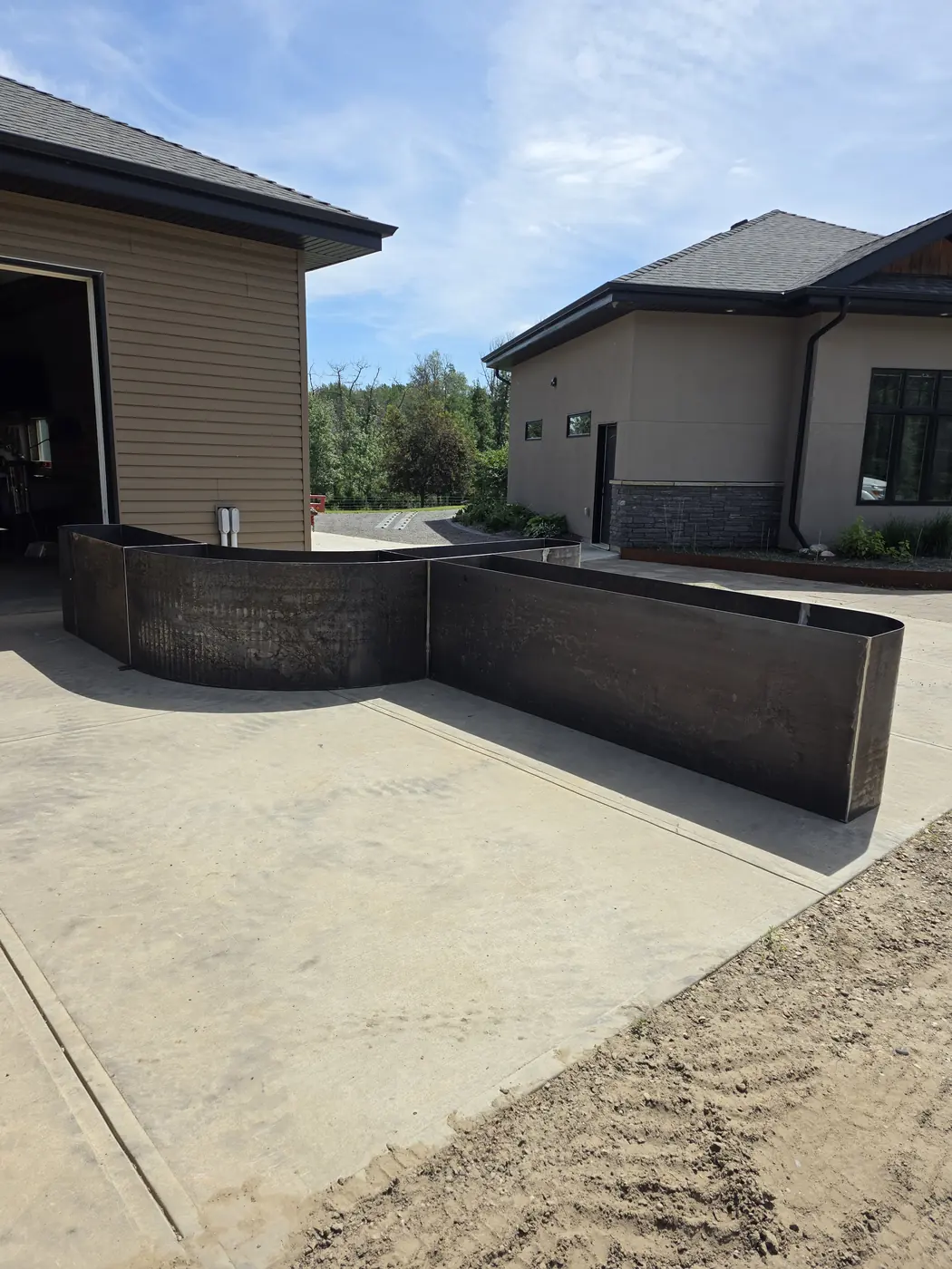 Modular Corten steel planter and bench installed across a concrete courtyard at a modern home