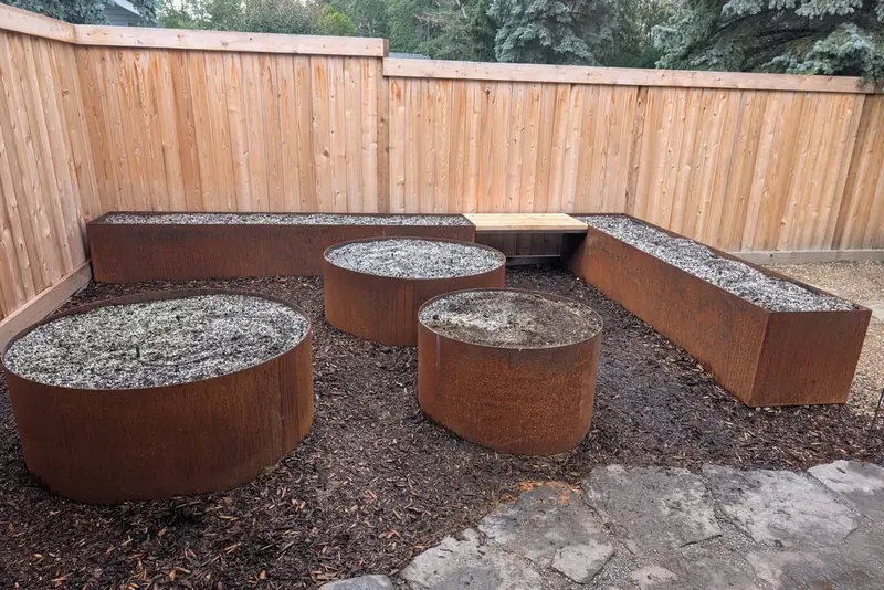 Corten steel round and trough planters with integrated cedar bench in a modern Alberta backyard