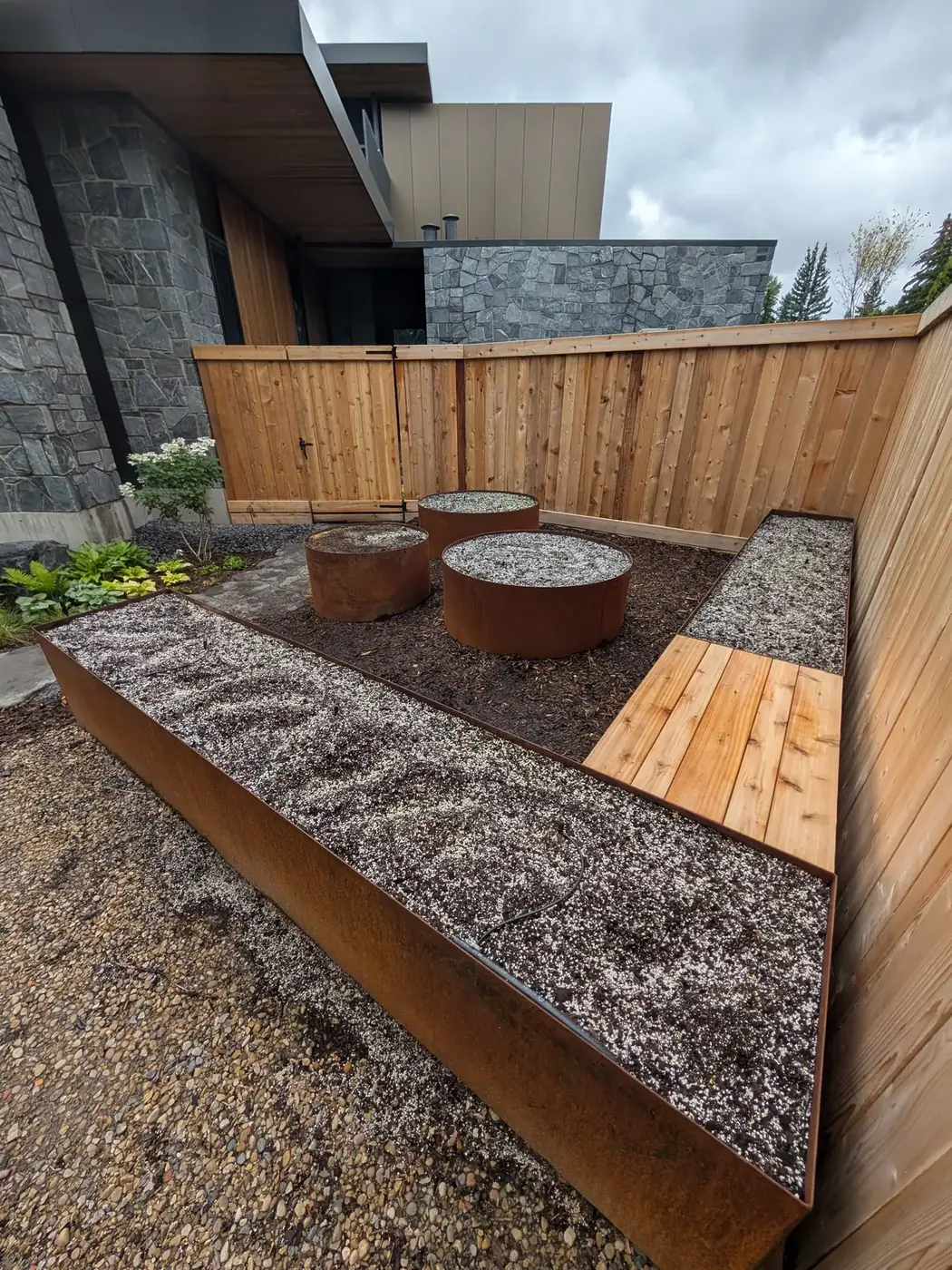 Corten steel planters in front of a modern stone and cedar home