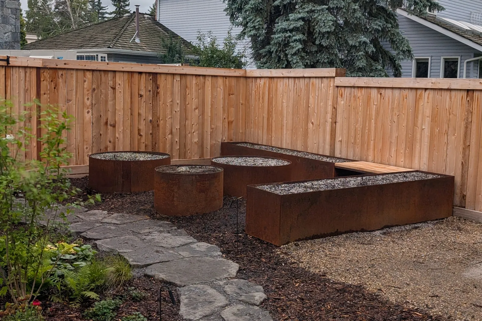 Wide view of a Corten planter installation with flagstone walkway