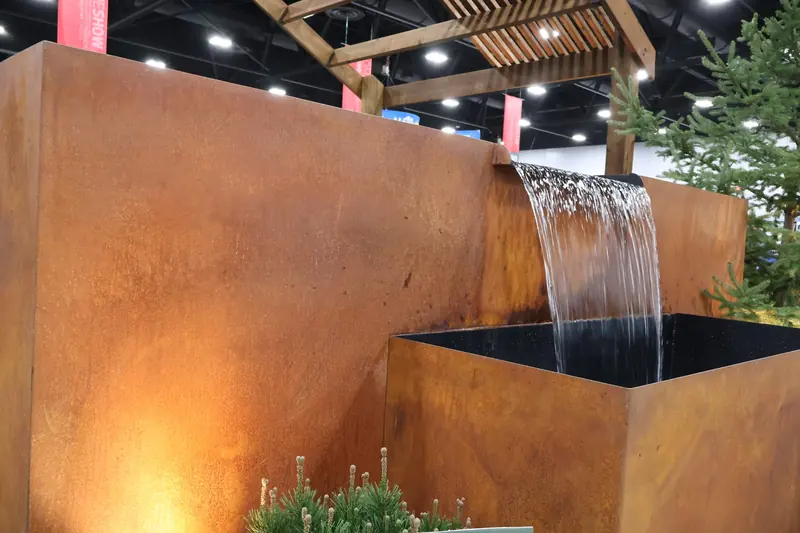 Corten steel waterfall wall sheeting into a basin at the Home & Garden Show booth