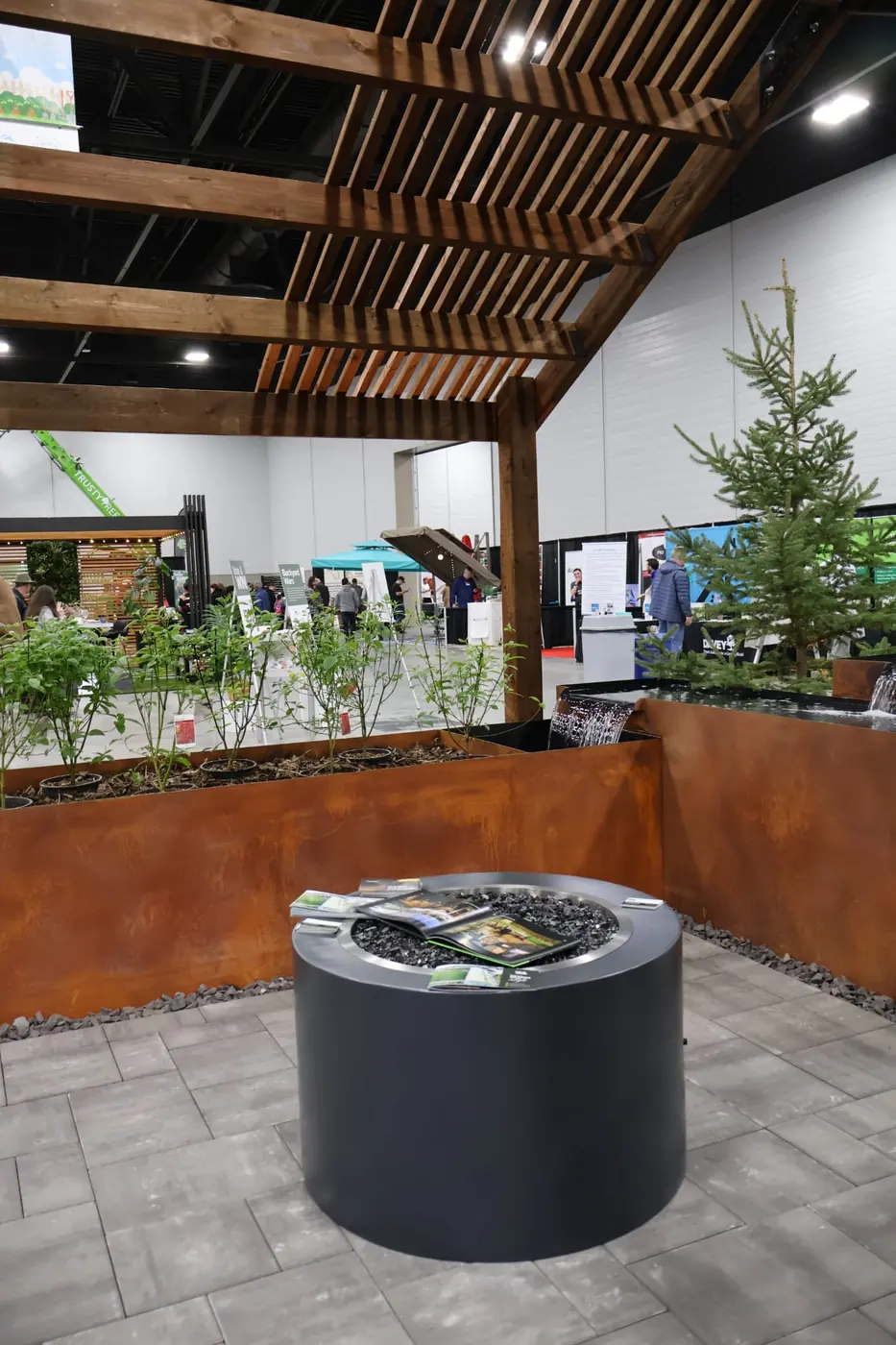Show booth walkway with Corten planters, turf borders, and a wood trellis